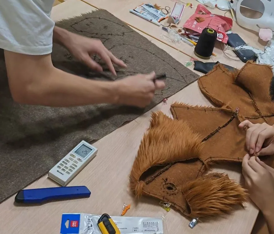 朋友们围着工作桌一起裁剪和缝制毛布